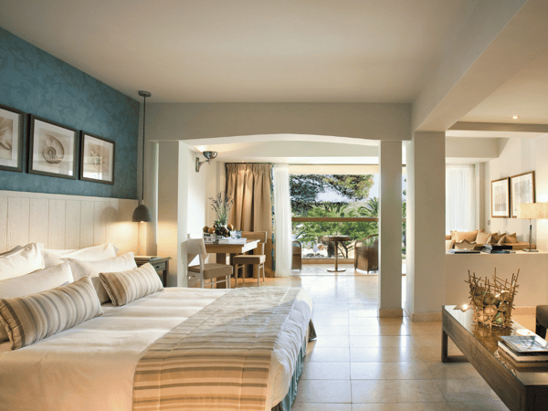 Junior Suite at Sani Beach with a double bed, lounge area, and balcony offering a panoramic sea view.