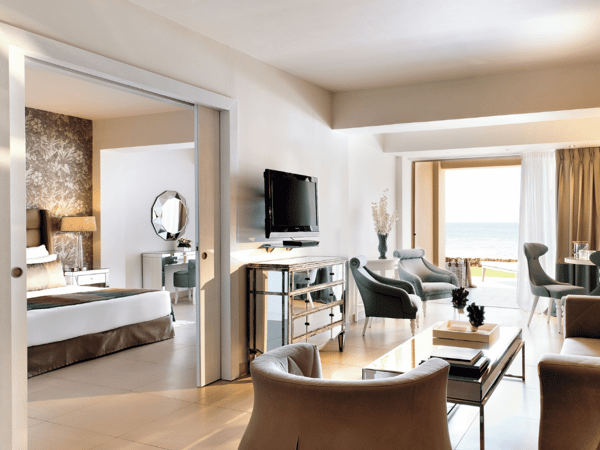 Interior of a one-bedroom family suite at Sani Beach, showcasing a living area with elegant furniture and a private terrace with sea views.