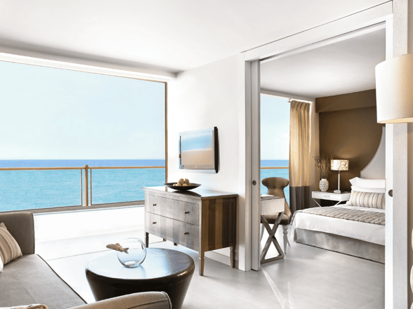 One-bedroom family suite at Sani Beach with modern furnishings and a sea view from a large window.