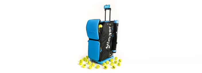 Slinger tennis ball launcher with a blue design, surrounded by yellow tennis balls, showcasing its portable and efficient tennis practice capabilities.