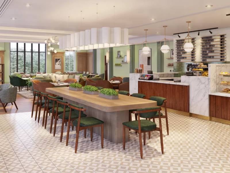 Spacious and elegant dining area at The Lensbury with a communal table, green chairs, coffee bar, and pendant lights.