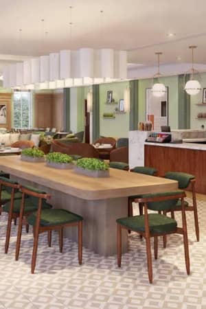 Spacious and elegant dining area at The Lensbury with a communal table, green chairs, coffee bar, and pendant lights.