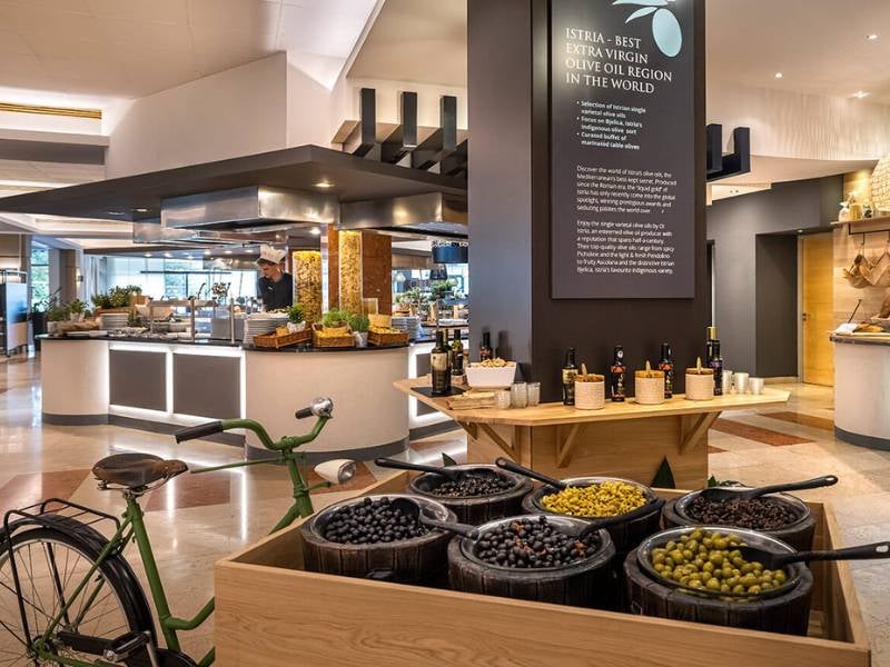 Dining area in Valamar resort with gourmet olive display and vintage bicycle, highlighting Istria as the best olive oil region.
