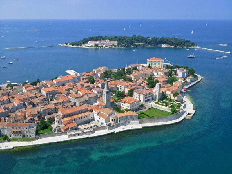 Aerial view of Poreč, Croatia, highlighting medieval architecture, the Euphrasian Basilica, and the surrounding Adriatic Sea.