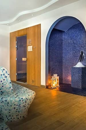 Luxurious spa room with mosaic-tiled steam room, contoured seating, wood panelled walls, and decorative lanterns.