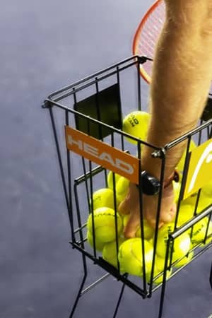 Close-up of a tennis ball basket with HEAD branding at Virgin Active Chiswick, on an indoor court.