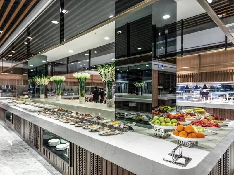 Lavish buffet with gourmet dishes and fresh fruits on a marble countertop, decorated with white flowers and modern mirrors at Vogue Gallery.
