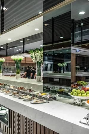 Lavish buffet with gourmet dishes and fresh fruits on a marble countertop, decorated with white flowers and modern mirrors at Vogue Gallery.
