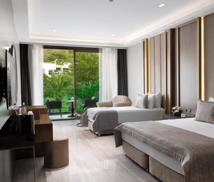 Vogue Superior Room interior with two beds, a work desk, TV, a seating area, and terrace access overlooking greenery.