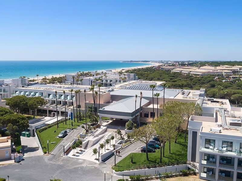 Aerial view of Barosa Park Hotel with its modern architecture and surrounding greenery, set against stunning coastal sea views.
