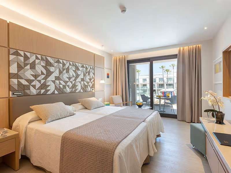 Luxurious hotel room at Barosa Park with a double bed, modern decor, and private balcony overlooking palm trees.