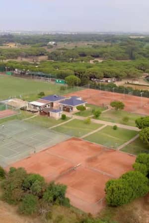 Aerial view of Barosa Park's tennis courts, featuring clay courts and verdant surroundings with additional sports facilities and a road nearby.