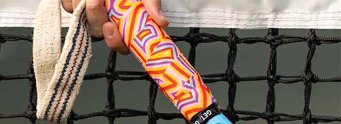 Colourful tennis racket grip with geometric patterns, held in front of a tennis net, from Get a Grip collection.