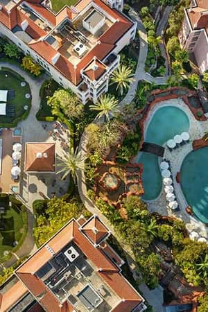 Aerial view of Hilton Vilamoura featuring two large outdoor pools, sun loungers, landscaped gardens, and hotel buildings.