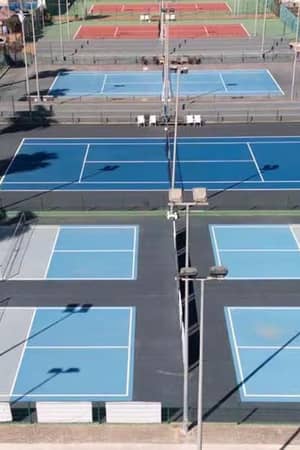 Wide shot of several blue and red tennis courts at Hotel Vincci with clear white markings and surrounding nets.