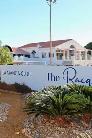 La Manga Club hotel exterior with garden and The Racquets Club sign, featuring palm trees and bright sky.