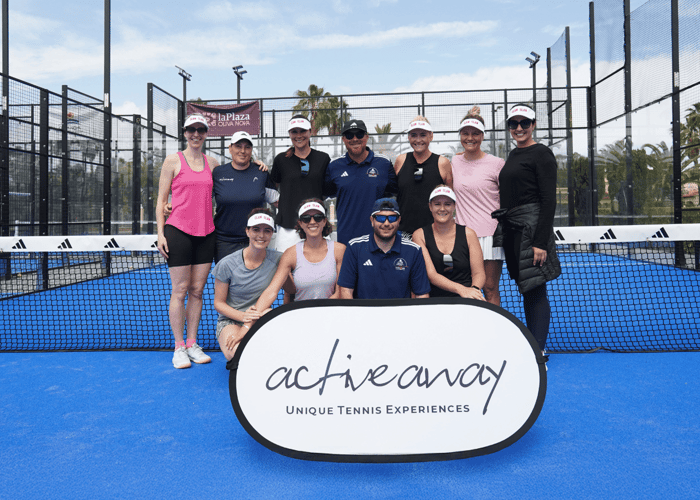 Group of smiling padel players and coaches on a blue court with an Active Away sign.