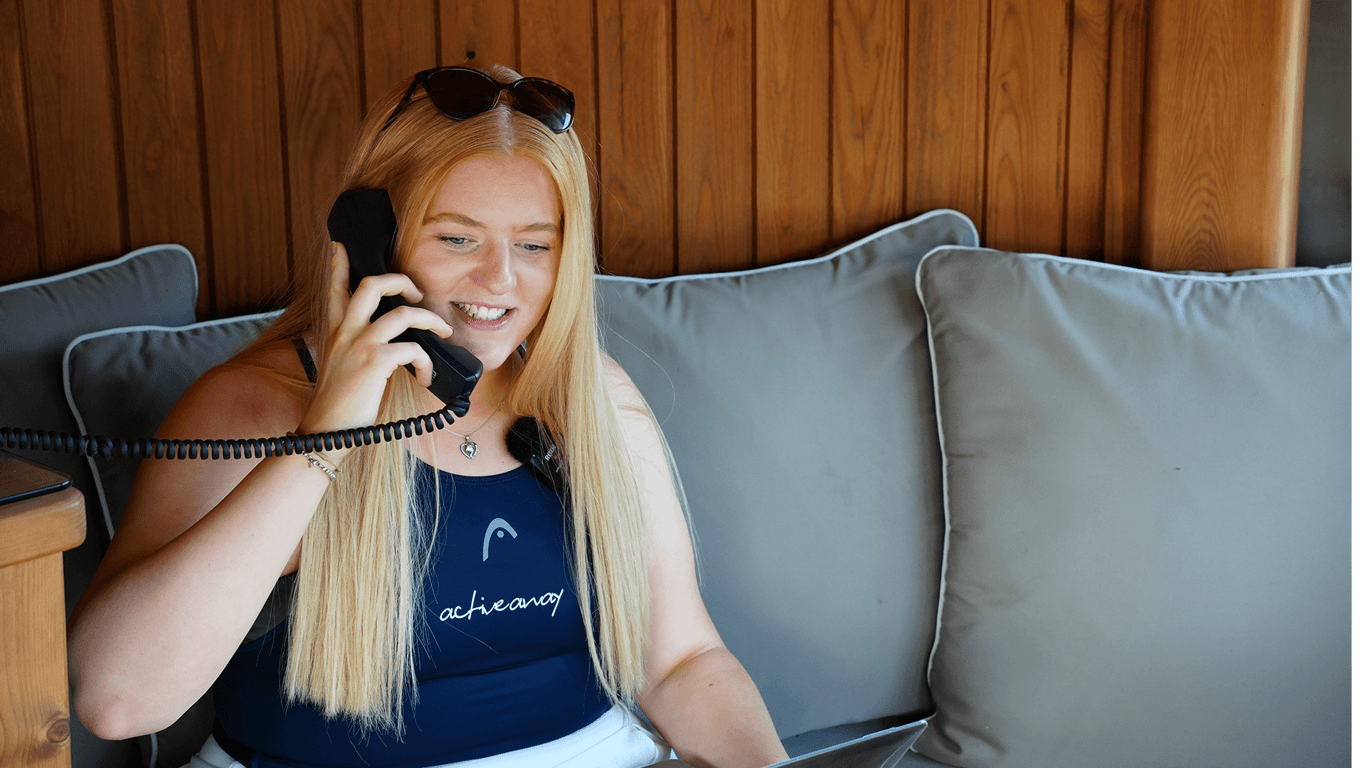 Smiling woman in Active Away top taking a phone call while seated on a sofa.