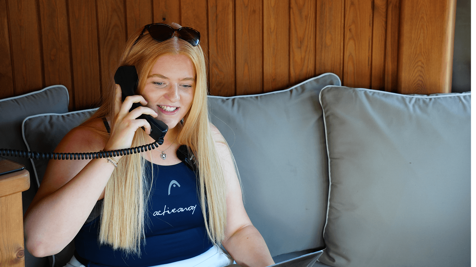 Smiling woman in Active Away top taking a phone call while seated on a sofa.