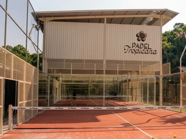 Brand deck mock-up of a terracotta padel court in front of a covered building with Padel Tropicana signage.