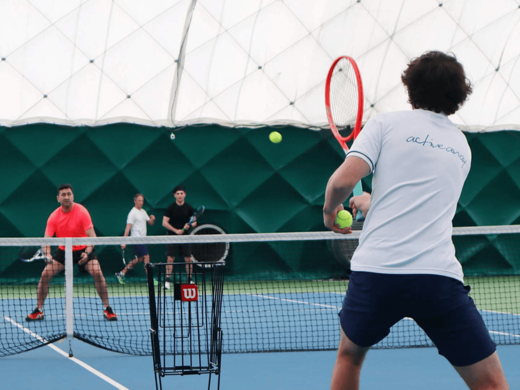 Players practise volleys during an indoor Active Away tennis session.