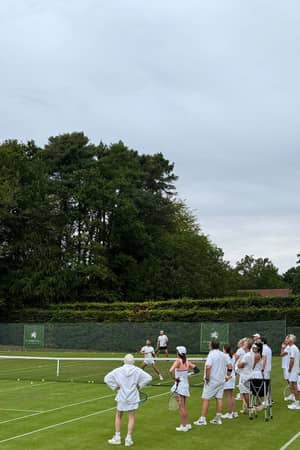 An Active Away coach leading a tennis session on the grass courts at St George's Hill.