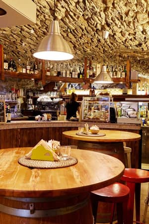 Warm stone-walled bar in Alagna with wooden tables and stools