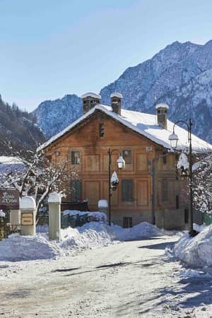 Snow-covered traditional buildings in Alagna beneath the surrounding mountains