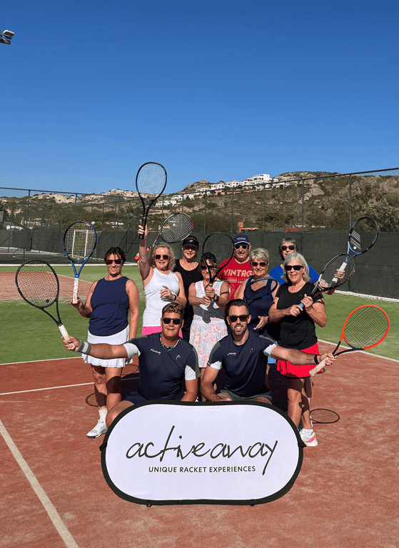Group of adults posing with tennis rackets on court with Active Away sign.